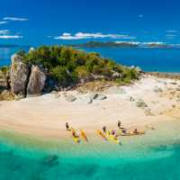 Sea kayaking group beaches kayaks on a granite islet, Whitsunday Islands, Queensland.
