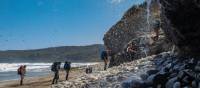 Trekking behind a waterfall on the South Coast Track | John Dalton