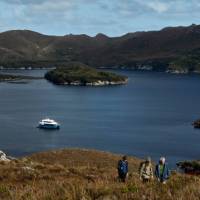 Guests on hike to Mt Stokes, Odalisque III in the entrance to Bathurst Channel | Tim Grey