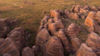 Indulge in the enchanting spectacle of a sunset casting its warm hues against the iconic Beehive Range in the Bungle Bungles | Tourism Western Australia