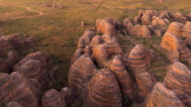 Indulge in the enchanting spectacle of a sunset casting its warm hues against the iconic Beehive Range in the Bungle Bungles | Tourism Western Australia